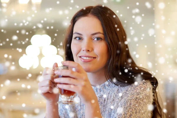 Smiling young woman drinking tea at cafe — Stock Photo, Image