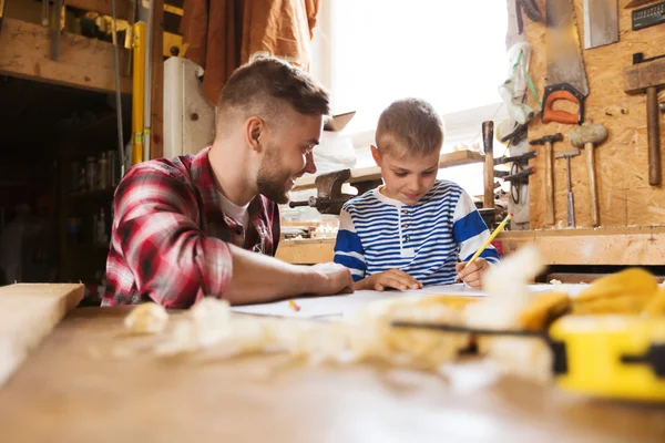 Счастливые отец и сын с чертежом в мастерской — стоковое фото