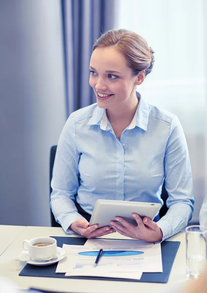 Улыбающаяся женщина держит планшетный компьютер в офисе — стоковое фото