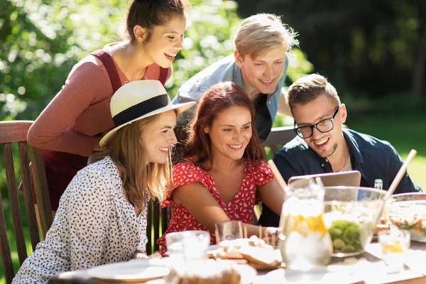 Amigos con tablet PC en la cena en el jardín de verano — Foto de Stock