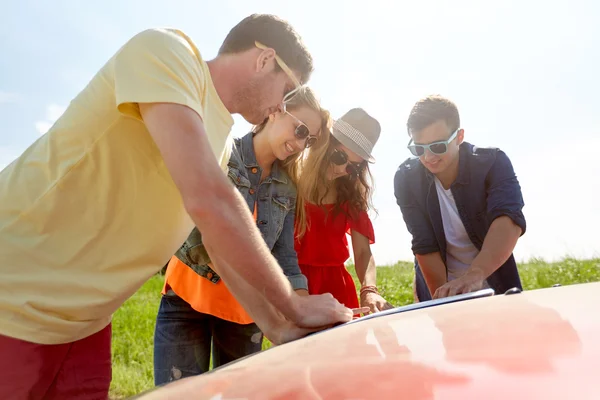 Amigos felices con mapa y coche de búsqueda ubicación — Foto de Stock