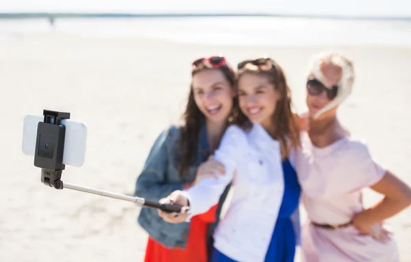 Women with selfie stick and smartphone on beach — Stock Photo, Image