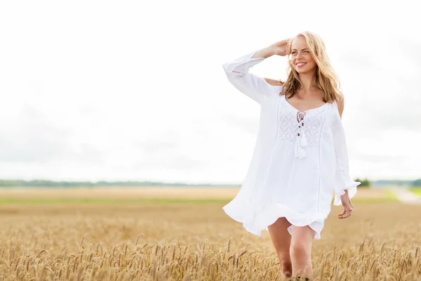 Улыбающаяся молодая женщина в белом платье на зерновом поле — стоковое фото
