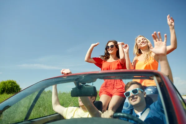 Amigos felizes dirigindo em carro cabriolet — Fotografia de Stock