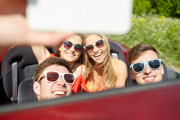 Amigos conduciendo en coche cabriolet y tomando selfie — Foto de Stock