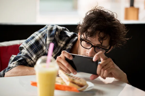 Homme avec smartphone photographier de la nourriture au café — Photo