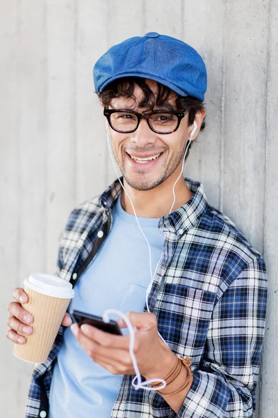 Man med hörlurar och smartphone dricka kaffe — Stockfoto