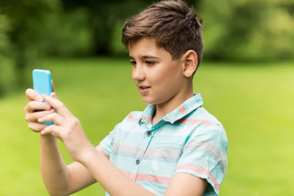 Chlapec s smartphone hrát hru v letním parku — Stock fotografie
