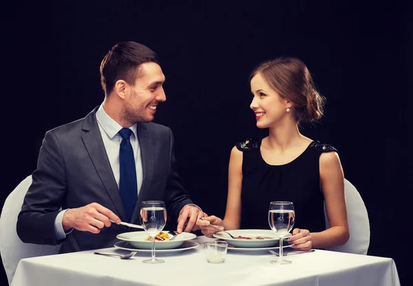 Sonriente pareja comiendo plato principal en restaurante —  Fotos de Stock