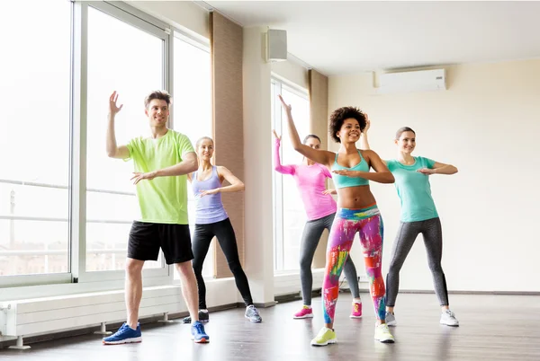 Group of smiling people dancing in gym or studio — Stock Photo, Image