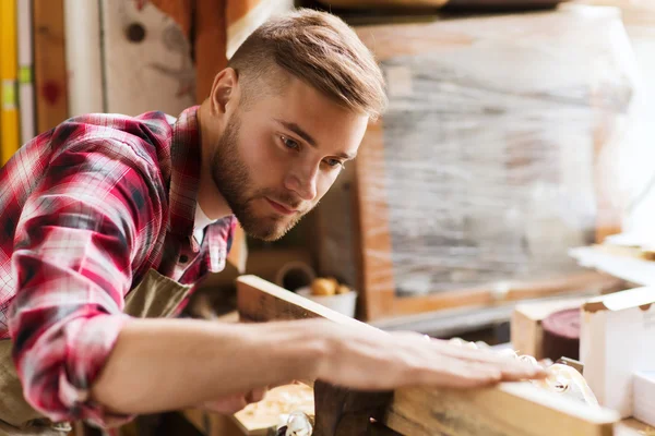Плотник, работающий с деревянной доской в мастерской — стоковое фото