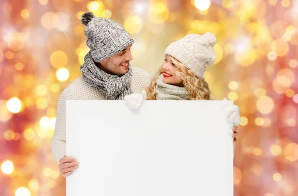 Casal em roupas de inverno com placa branca em branco — Fotografia de Stock
