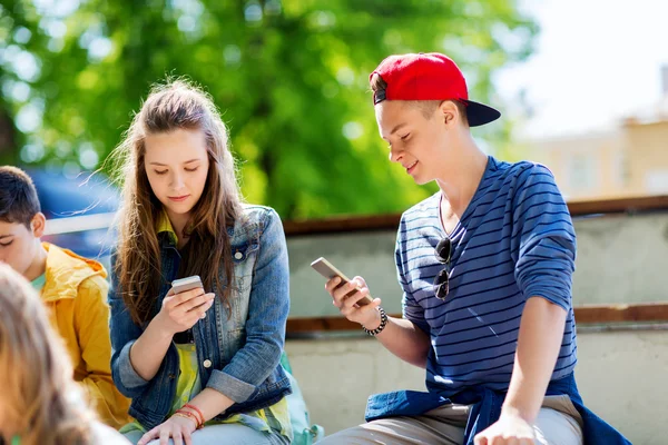 Счастливые друзья-подростки со смартфонами на улице — стоковое фото