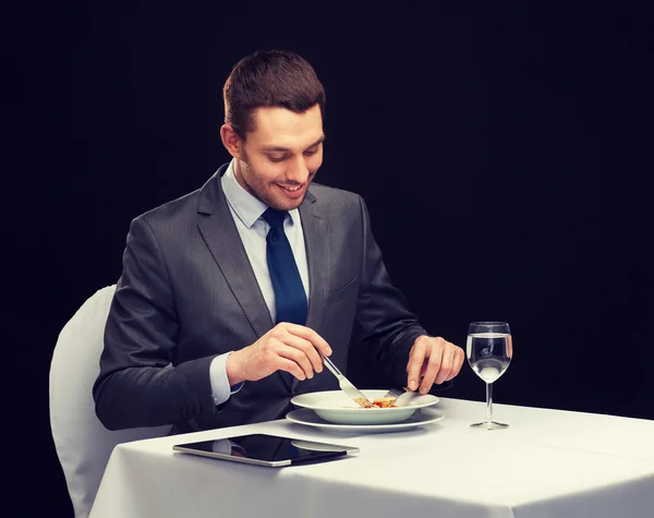 Hombre sonriente con la tableta PC comer plato principal —  Fotos de Stock