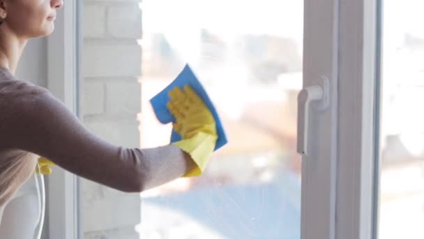 Женщина в перчатках моет окно тряпкой — стоковое видео