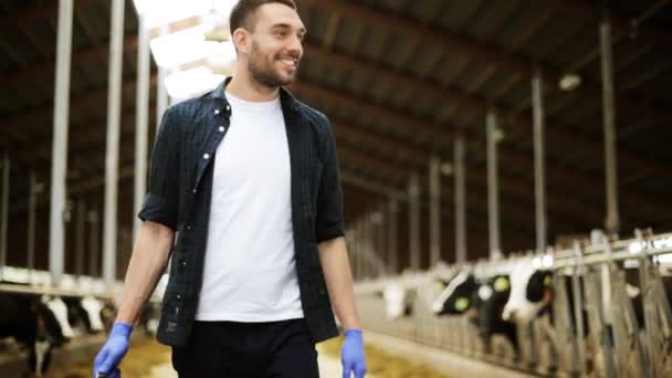 牛と農場を歩いているバケツを持つ男 — ストック動画