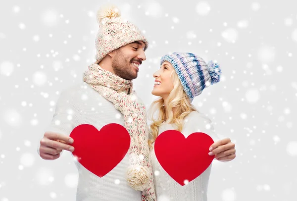 Χαμογελώντας ζευγάρι στο χειμωνιάτικα ρούχα με κόκκινες καρδιές — Φωτογραφία Αρχείου