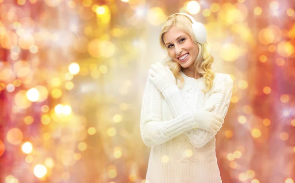 Mosolygó fiatal nő téli fülvédő és pulóver — Stock Fotó