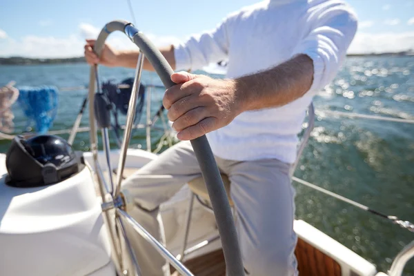Ανώτερος άνθρωπος στο τιμόνι σχετικά με βάρκα ή σκάφος ιστιοπλοΐας στην θάλασσα — Φωτογραφία Αρχείου