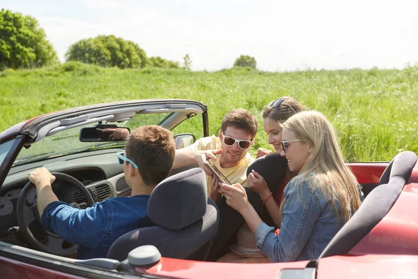 Amigos com tablet pc dirigindo em carro cabriolet — Fotografia de Stock