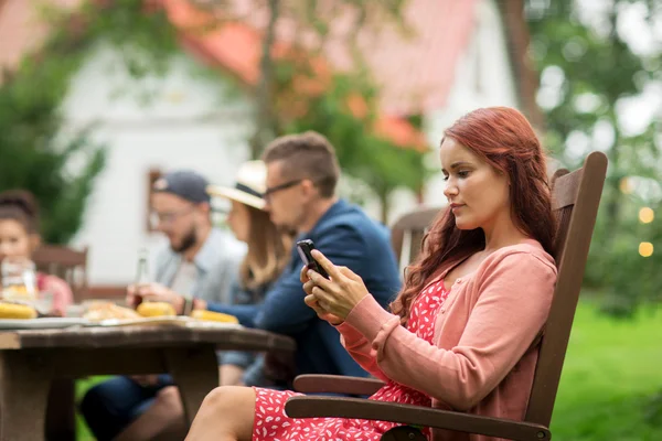 Žena s smartphone a přáteli na letních party — Stock fotografie