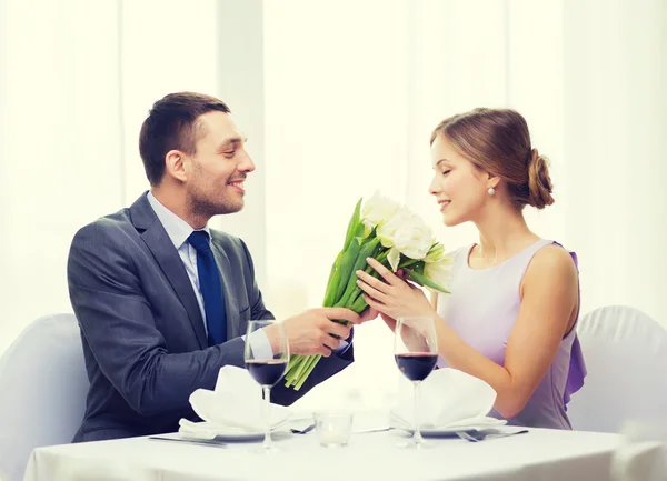 Smiling man giving flower bouquet at restaurant — Stock Photo, Image