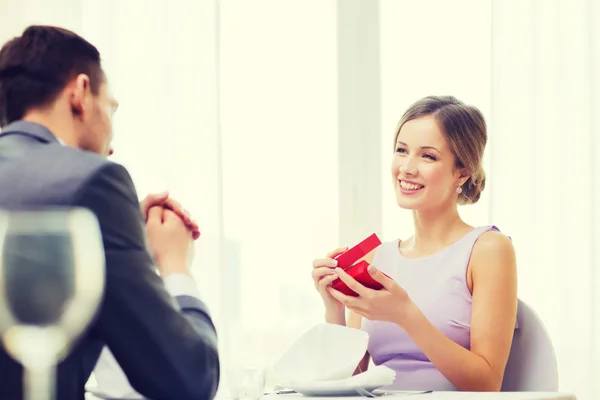 Excited young woman looking at boyfriend with box — Stock Photo, Image