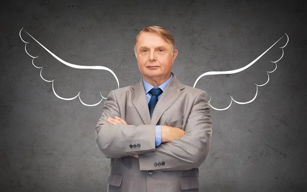 Senior businessman with angel wings over gray — Stock Photo, Image