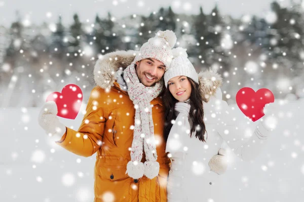 Casal feliz com corações vermelhos sobre paisagem de inverno — Fotografia de Stock