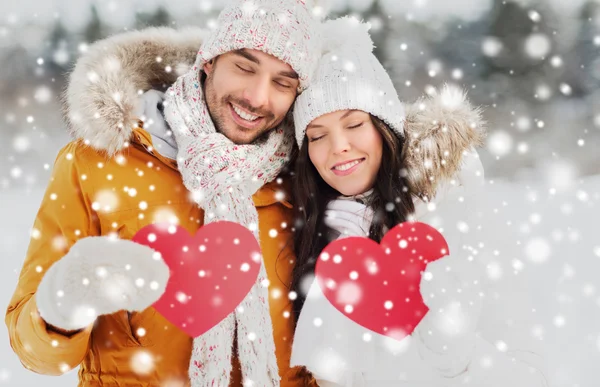 Casal feliz com corações vermelhos sobre paisagem de inverno — Fotografia de Stock