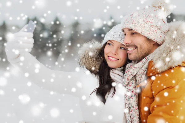 Feliz pareja tomando selfie por teléfono inteligente en invierno —  Fotos de Stock