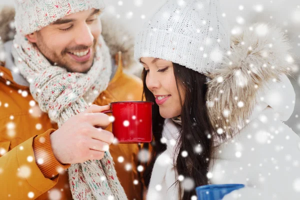 Happy couple with tea cups over winter landscape — Stock Photo, Image