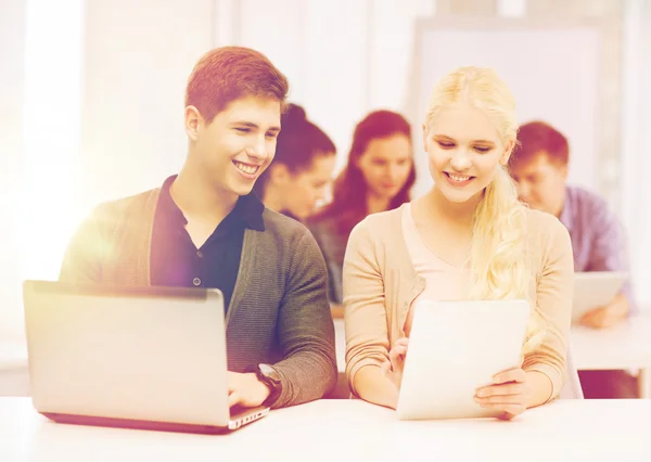 Dos estudiantes sonrientes con ordenador portátil y tableta PC — Foto de Stock