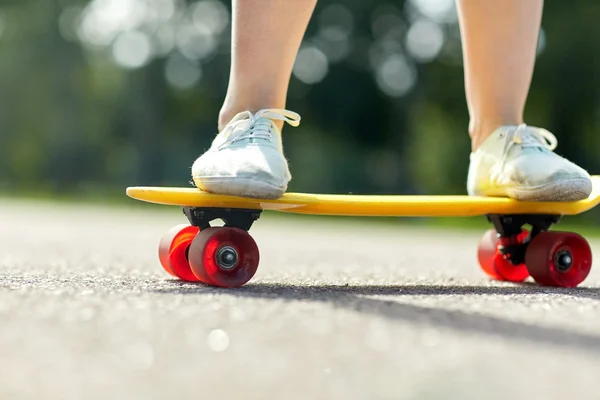 Close up van vrouwelijke voeten rijden korte skateboard — Stockfoto