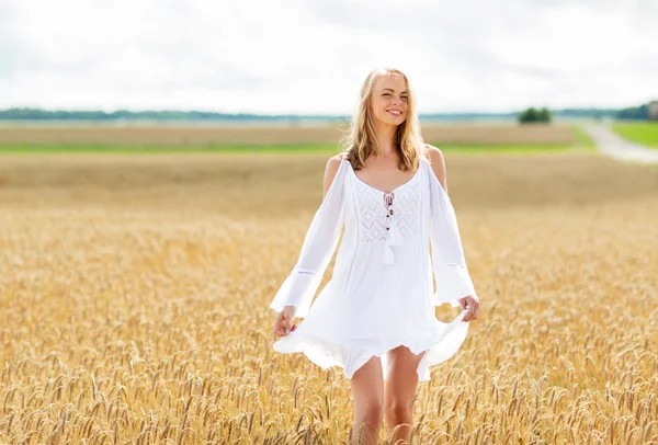 Усміхнена молода жінка в білій сукні на зерновому полі — стокове фото