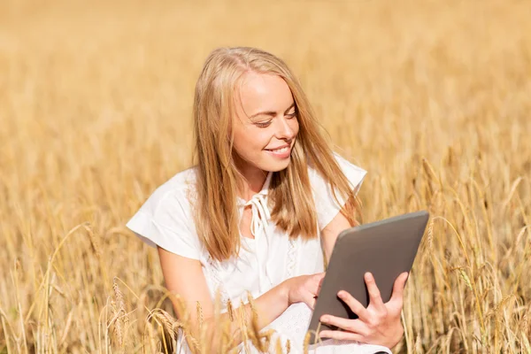 Gelukkig jong vrouw met tablet pc op graan veld — Stockfoto