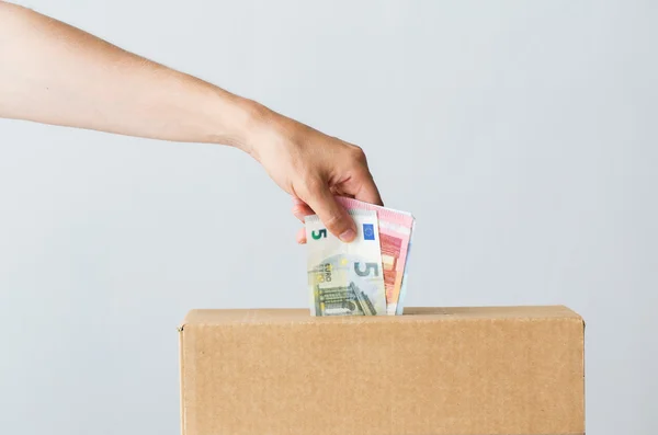 Человек кладет деньги евро в коробку для пожертвований — стоковое фото