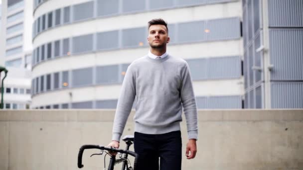 Junger Mann läuft mit Fahrrad die Stadtstraße entlang — Stockvideo