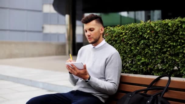 Человек с блокнотом или дневником, пишущий на городской улице — стоковое видео