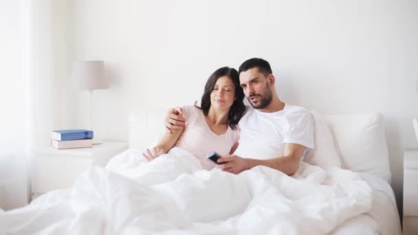 Happy couple watching tv in bed at home — Stock Video