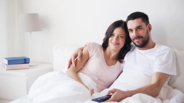 Happy couple watching tv in bed at home — Stock Video