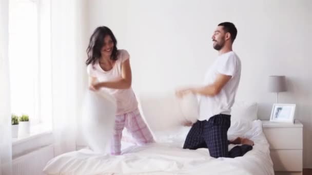 Feliz pareja teniendo almohada lucha en cama en casa — Vídeo de stock