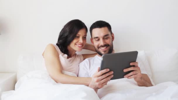 Улыбающаяся пара в постели с планшетным компьютером — стоковое видео