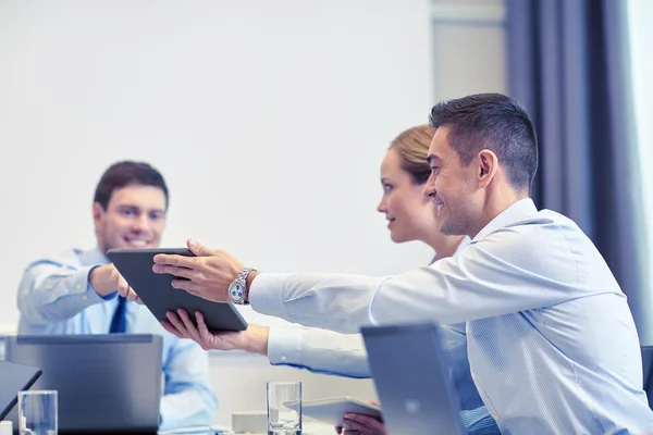 Souriants hommes d'affaires avec tablette PC dans le bureau — Photo