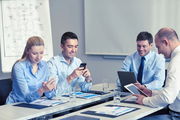 Glimlachende mensen uit het bedrijfsleven met gadgets in office — Stockfoto