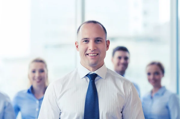 Hombre de negocios sonriente con colegas en el cargo — Foto de Stock