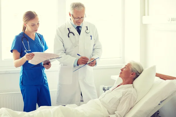 Médico e enfermeira visitando mulher idosa no hospital — Fotografia de Stock