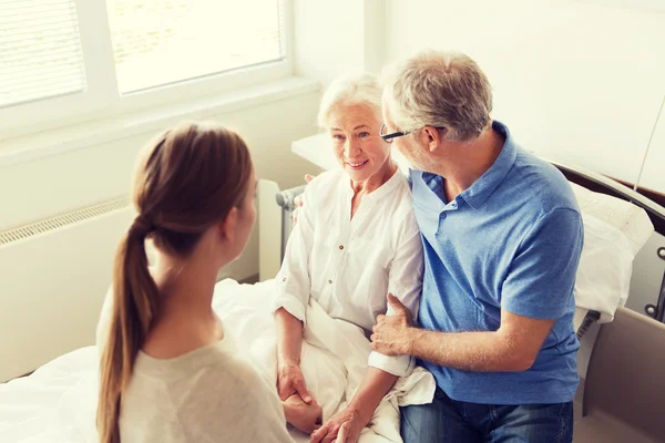 Lykkelig familie på besøk hos eldre kvinne på sykehuset – stockfoto