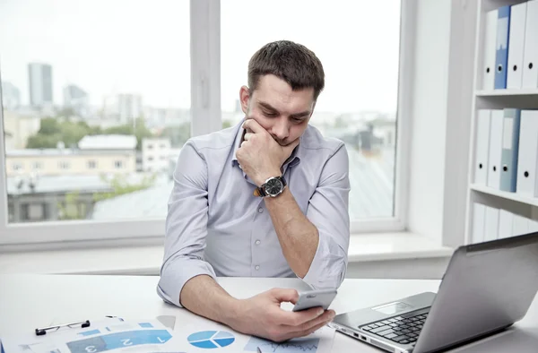 Hombre de negocios con smartphone y portátil en la oficina —  Fotos de Stock