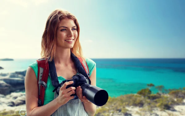 Happy woman with backpack and camera over seashore — 图库照片